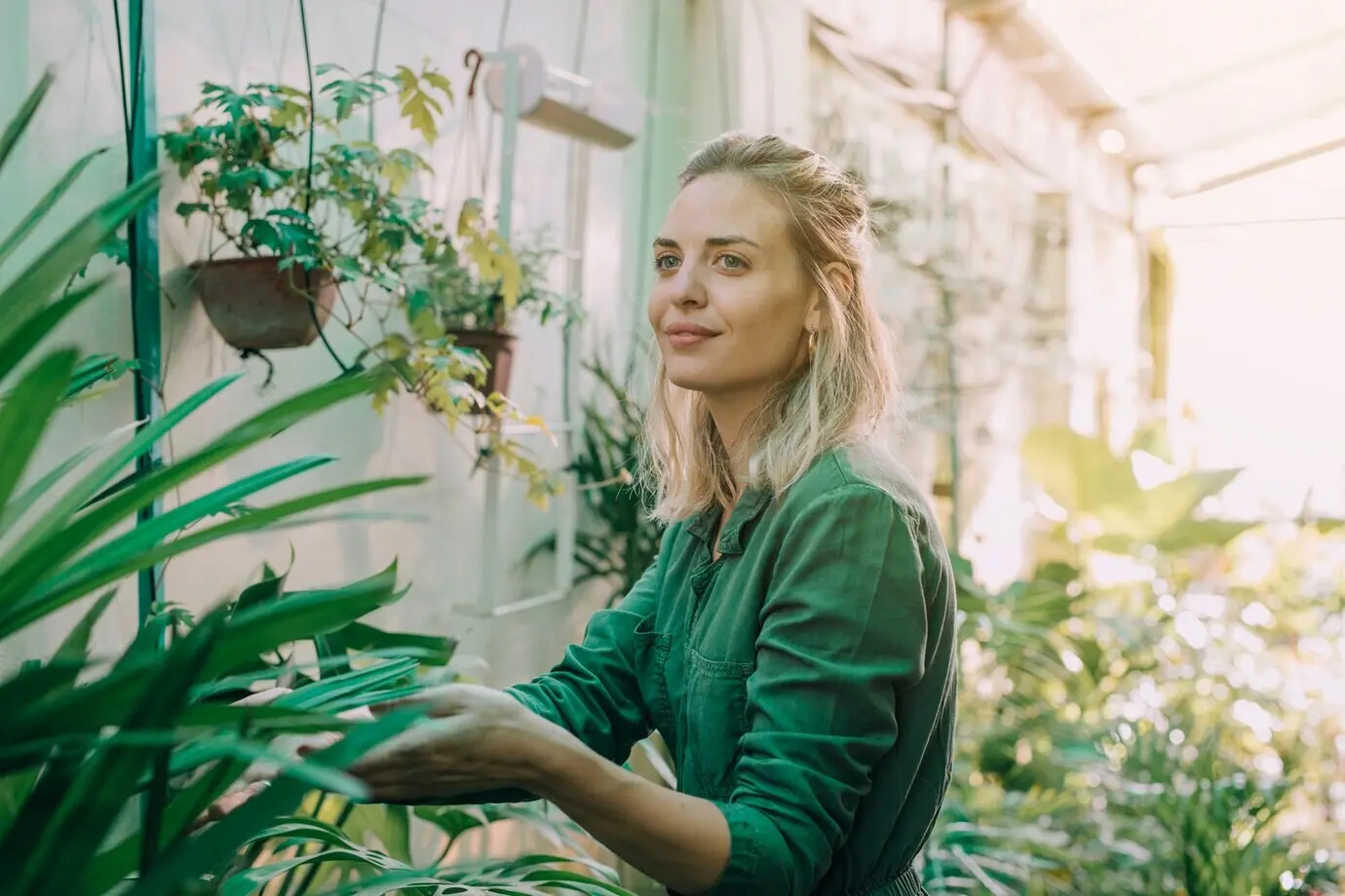 Mujer joven y atractiva, sonriente, que trabaja en el vivero de plantas.